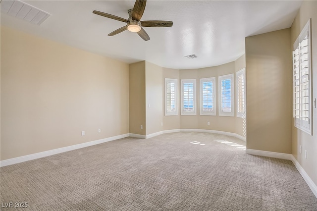 unfurnished room with visible vents, light colored carpet, a ceiling fan, and baseboards