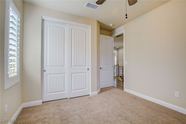 unfurnished bedroom featuring light colored carpet, visible vents, a closet, and baseboards