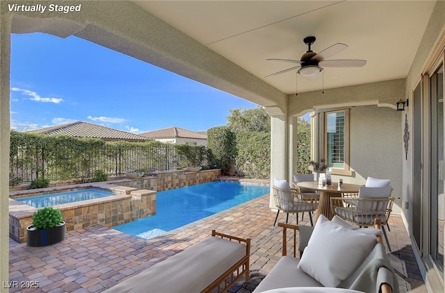 view of pool featuring outdoor dining space, a pool with connected hot tub, a patio, a fenced backyard, and ceiling fan