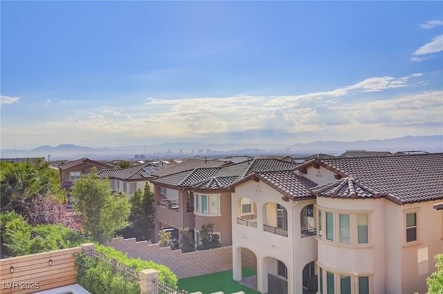 exterior space featuring a residential view, a tile roof, stucco siding, a balcony, and a mountain view