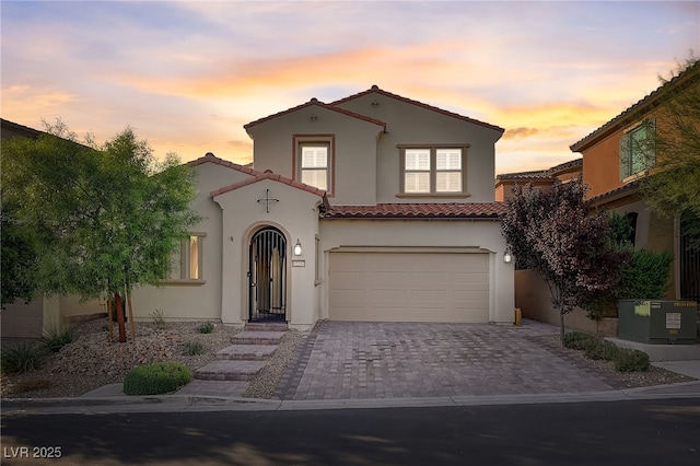 mediterranean / spanish home with cooling unit, stucco siding, a garage, a tiled roof, and decorative driveway