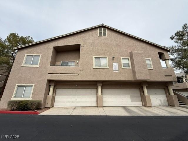 view of front facade with a garage, driveway, and stucco siding