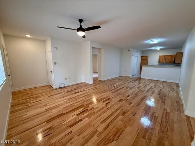 unfurnished living room featuring ceiling fan, light wood-type flooring, and baseboards