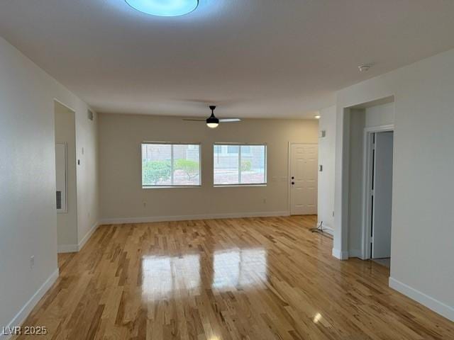 spare room with baseboards, light wood-style floors, and ceiling fan