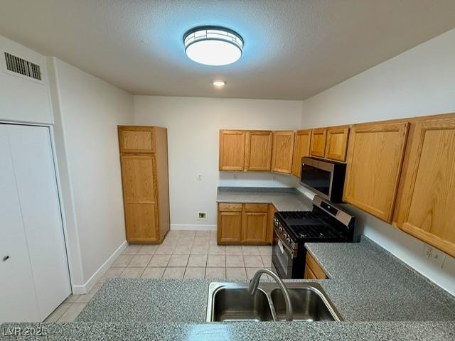 kitchen with visible vents, brown cabinets, a sink, appliances with stainless steel finishes, and light tile patterned floors