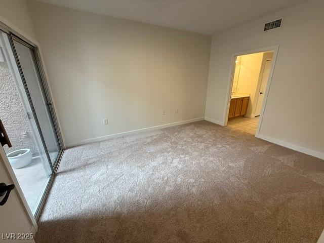 unfurnished bedroom with baseboards, light carpet, and visible vents