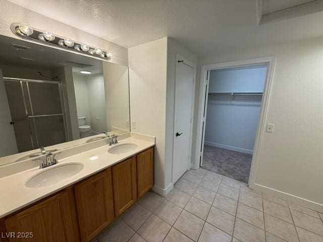 bathroom with double vanity, a stall shower, toilet, and a sink