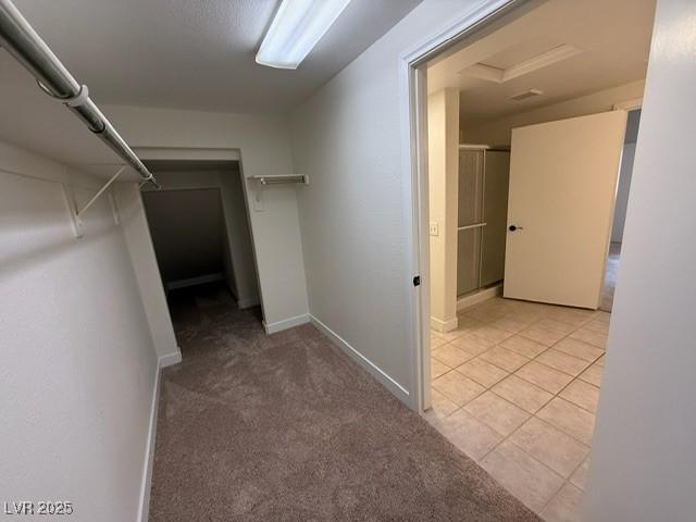 walk in closet featuring attic access, light tile patterned floors, and light carpet