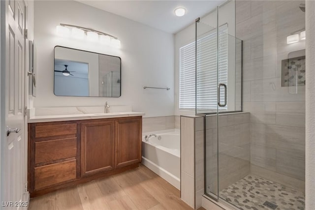 bathroom featuring a ceiling fan, a bath, and a shower stall