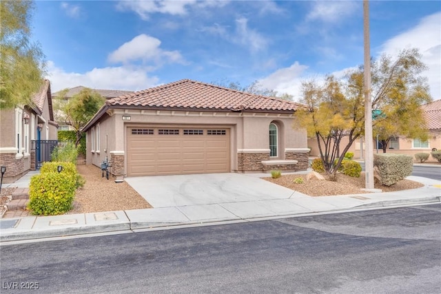 mediterranean / spanish home featuring stucco siding, stone siding, concrete driveway, a garage, and a tiled roof