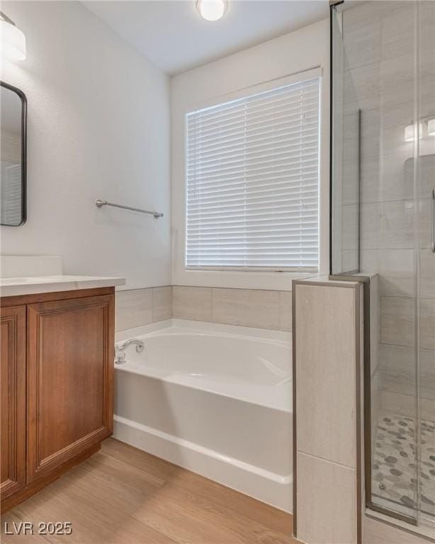 full bathroom featuring a bath, a stall shower, vanity, and wood finished floors