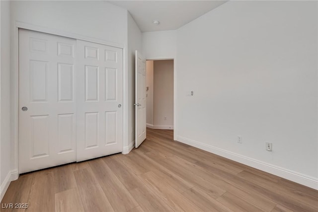 unfurnished bedroom featuring a closet, baseboards, and light wood-style floors