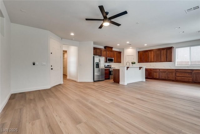 kitchen with visible vents, open floor plan, a kitchen bar, light countertops, and stainless steel appliances