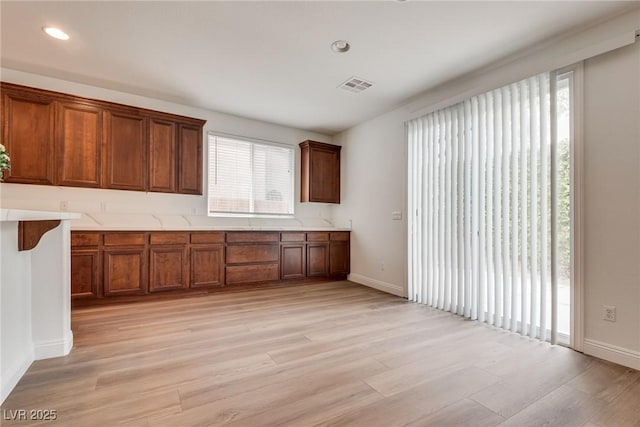 kitchen with visible vents, light wood finished floors, baseboards, and light countertops