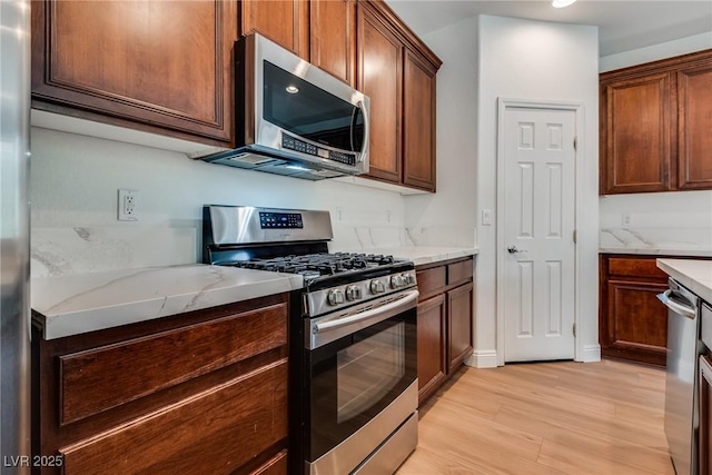 kitchen featuring light stone counters, stainless steel appliances, and light wood finished floors