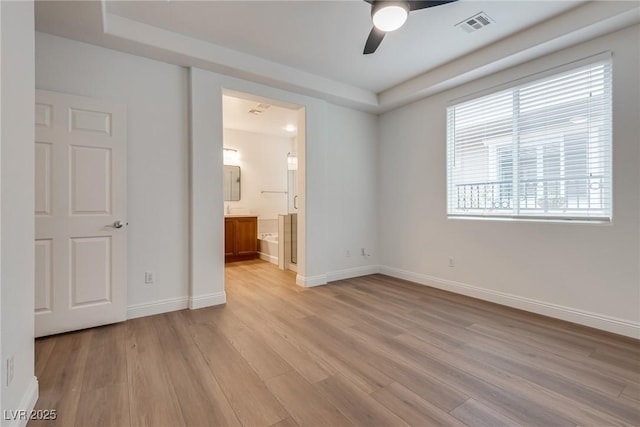 unfurnished bedroom featuring visible vents, ensuite bath, light wood-style floors, baseboards, and ceiling fan