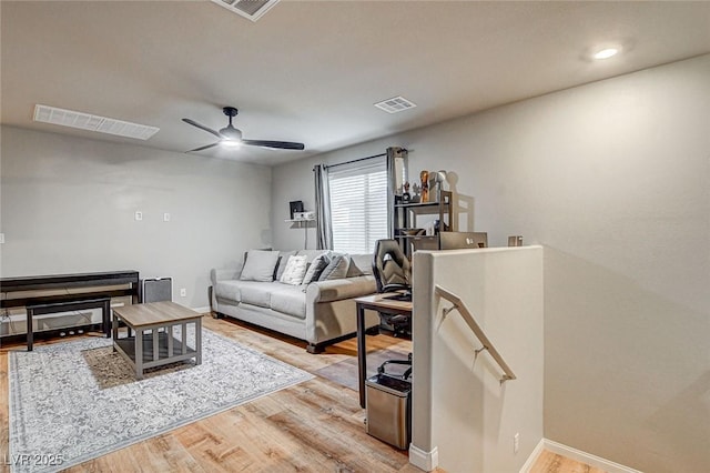 living area with visible vents, ceiling fan, baseboards, and light wood-style floors