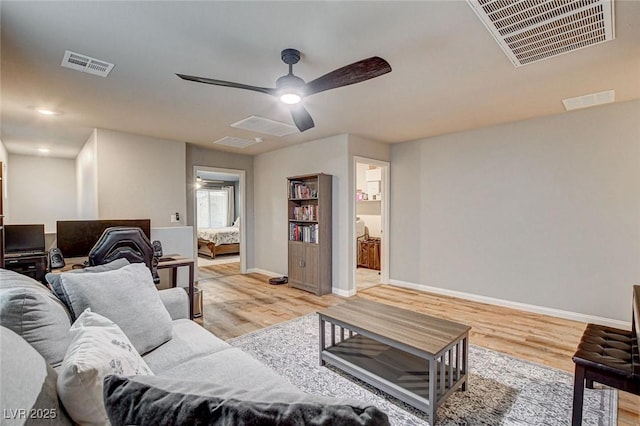 living room with a ceiling fan, light wood-style flooring, baseboards, and visible vents