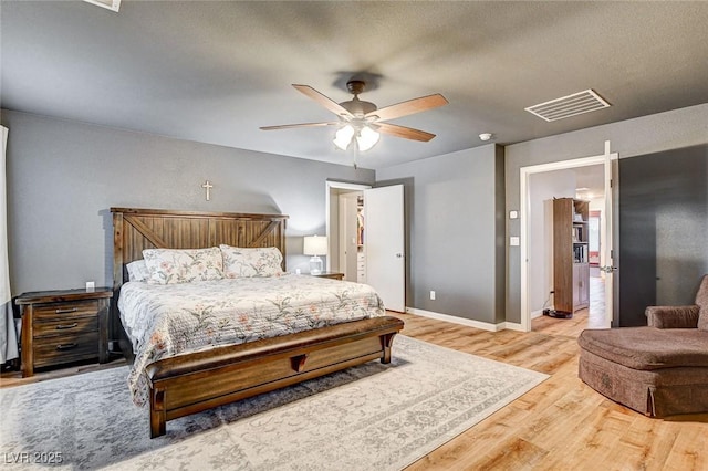 bedroom featuring baseboards, visible vents, light wood finished floors, and ceiling fan