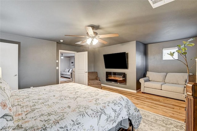 bedroom with ceiling fan, visible vents, baseboards, and wood finished floors