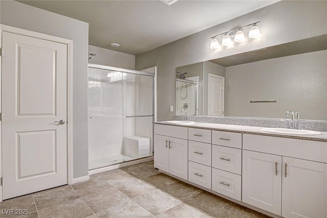 full bath with double vanity, a stall shower, and a sink