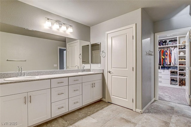 full bath featuring double vanity, a walk in closet, and a sink