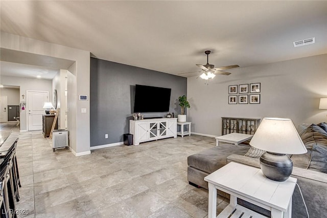 living area featuring baseboards, visible vents, and ceiling fan