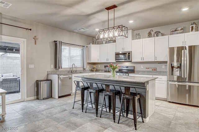 kitchen featuring a sink, stainless steel appliances, a kitchen breakfast bar, and visible vents