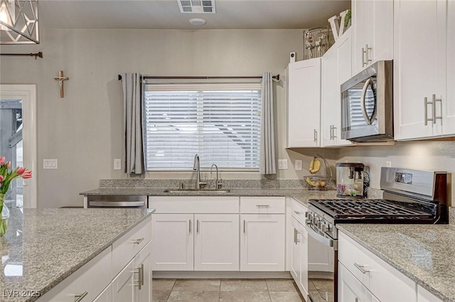 kitchen featuring visible vents, light stone countertops, white cabinets, stainless steel appliances, and a sink