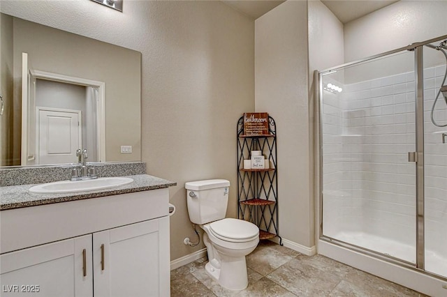 bathroom featuring baseboards, vanity, toilet, and a shower stall