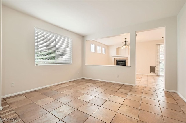 unfurnished room with light tile patterned flooring, a fireplace, and baseboards