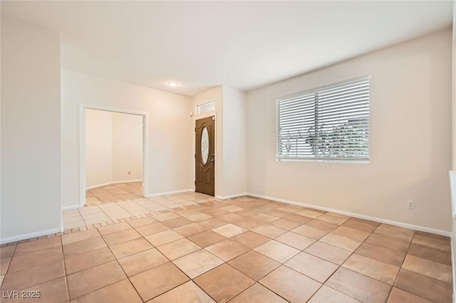 spare room with light tile patterned floors and baseboards