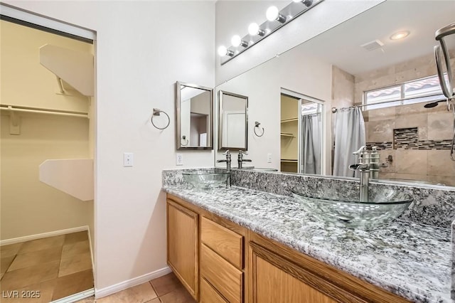 bathroom with tile patterned floors, a spacious closet, double vanity, and a sink