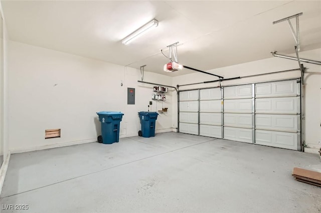 garage featuring electric panel, a garage door opener, and baseboards