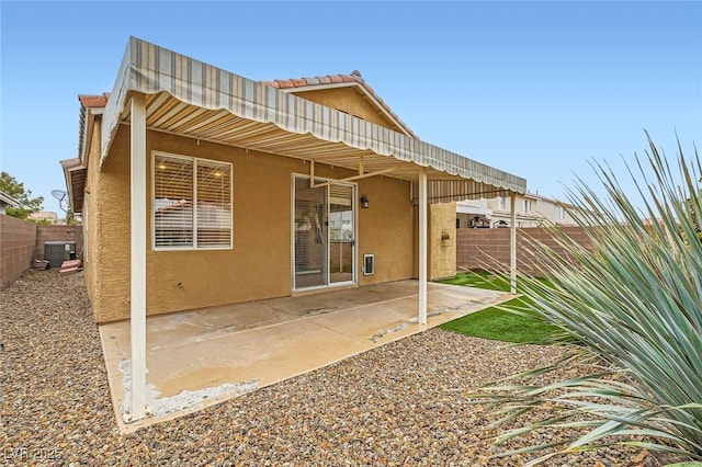 rear view of property with a fenced backyard, stucco siding, cooling unit, and a patio