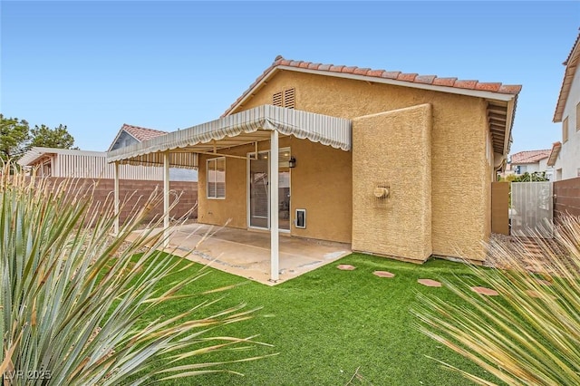 back of house with fence, stucco siding, a patio area, a tiled roof, and a lawn