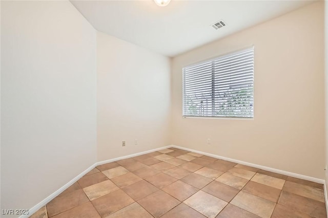 spare room featuring light tile patterned floors, visible vents, and baseboards