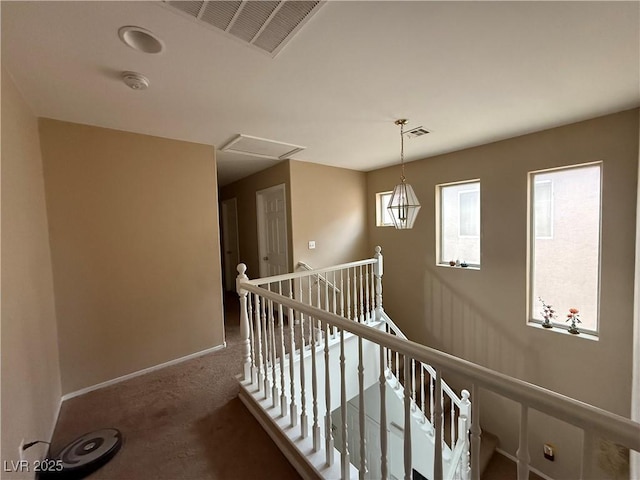 hall featuring carpet, attic access, an upstairs landing, and visible vents