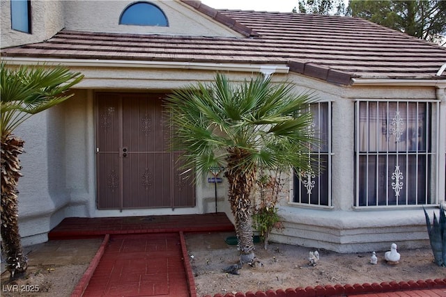 entrance to property featuring stucco siding and a tile roof