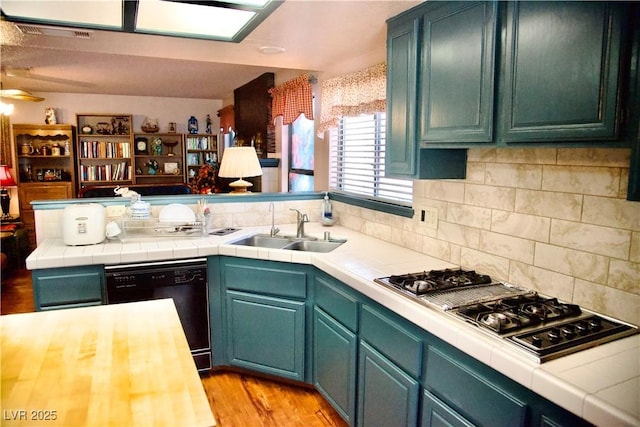 kitchen featuring dishwasher, stainless steel gas stovetop, tile countertops, and a sink