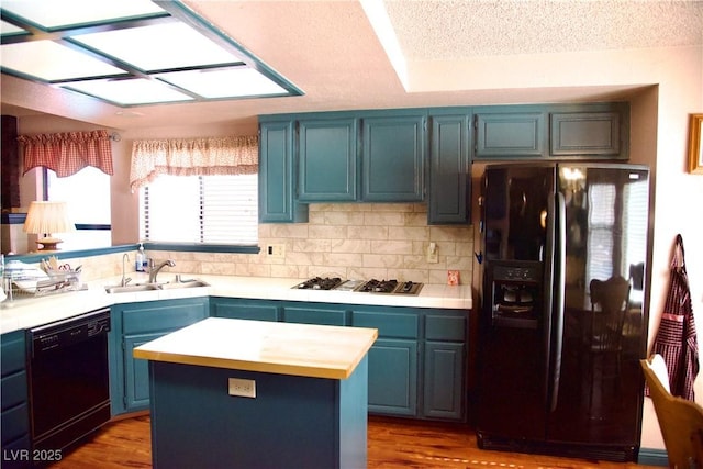 kitchen featuring tasteful backsplash, blue cabinetry, wood finished floors, black appliances, and a sink