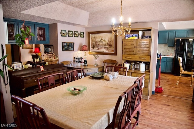 dining area featuring an inviting chandelier, light wood finished floors, and a textured ceiling