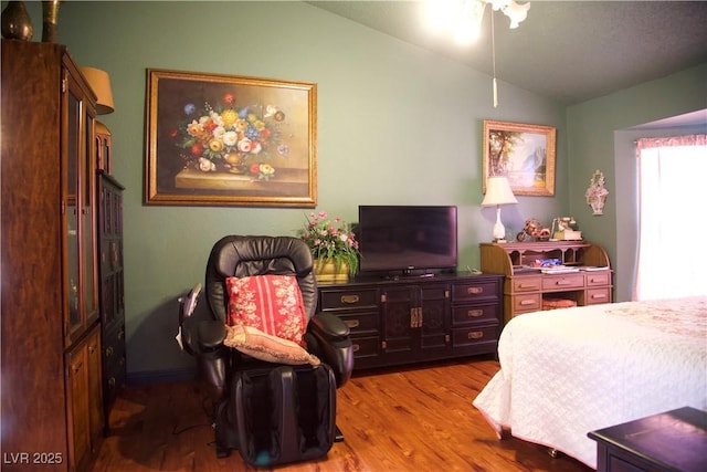 bedroom with vaulted ceiling and wood finished floors