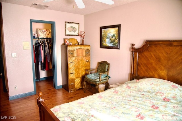 bedroom with wood finished floors, visible vents, a spacious closet, a closet, and a textured ceiling