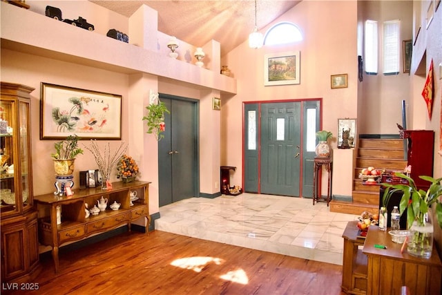 entrance foyer featuring high vaulted ceiling and wood finished floors