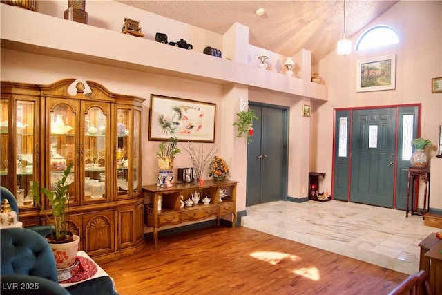 entrance foyer featuring a textured ceiling, wood finished floors, and high vaulted ceiling