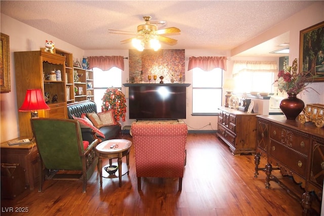 living room featuring wood finished floors, a textured ceiling, a healthy amount of sunlight, and ceiling fan