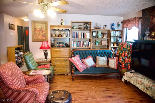 living area with a textured ceiling, ceiling fan, and wood finished floors