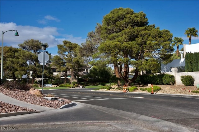 view of road featuring curbs, traffic signs, street lights, and sidewalks