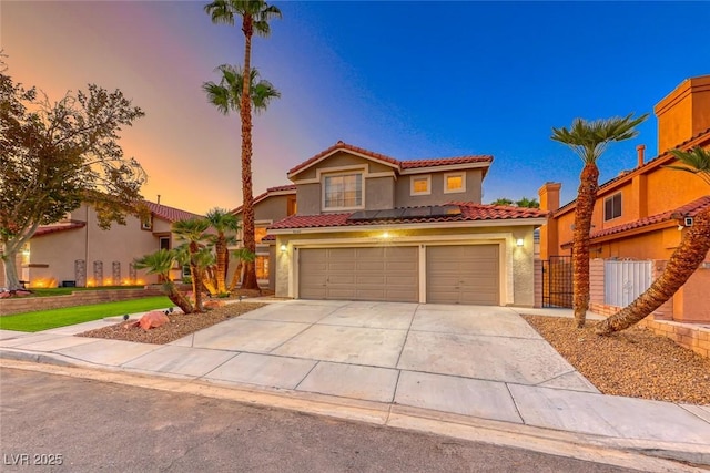 mediterranean / spanish-style home featuring fence, stucco siding, concrete driveway, a garage, and a tiled roof